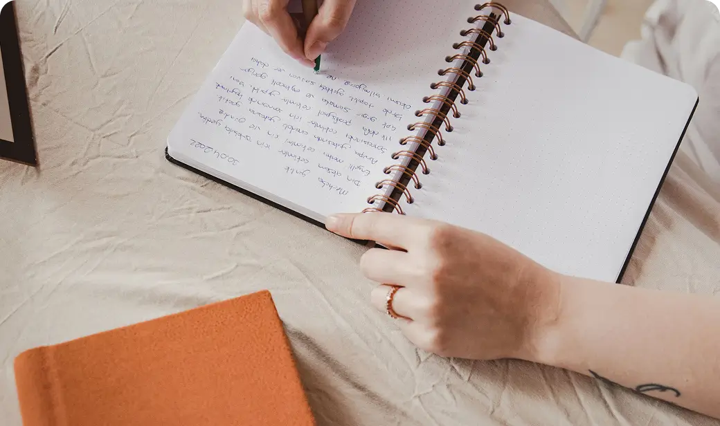 Writer planning a novel outline at a desk with coffee and books piled nearby