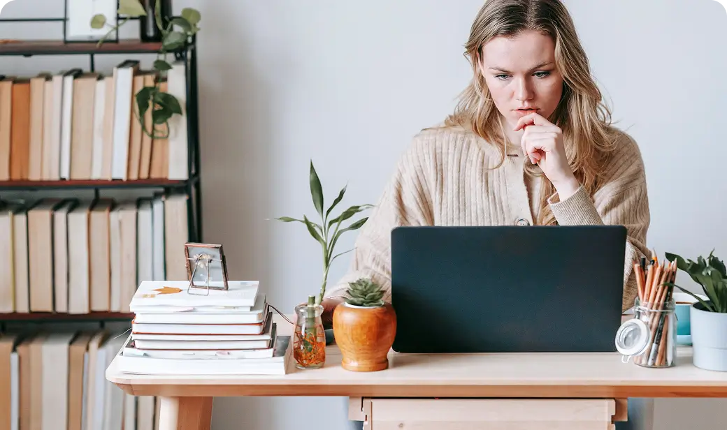 Woman writing her novel at her desk, with a shelf of books behind her